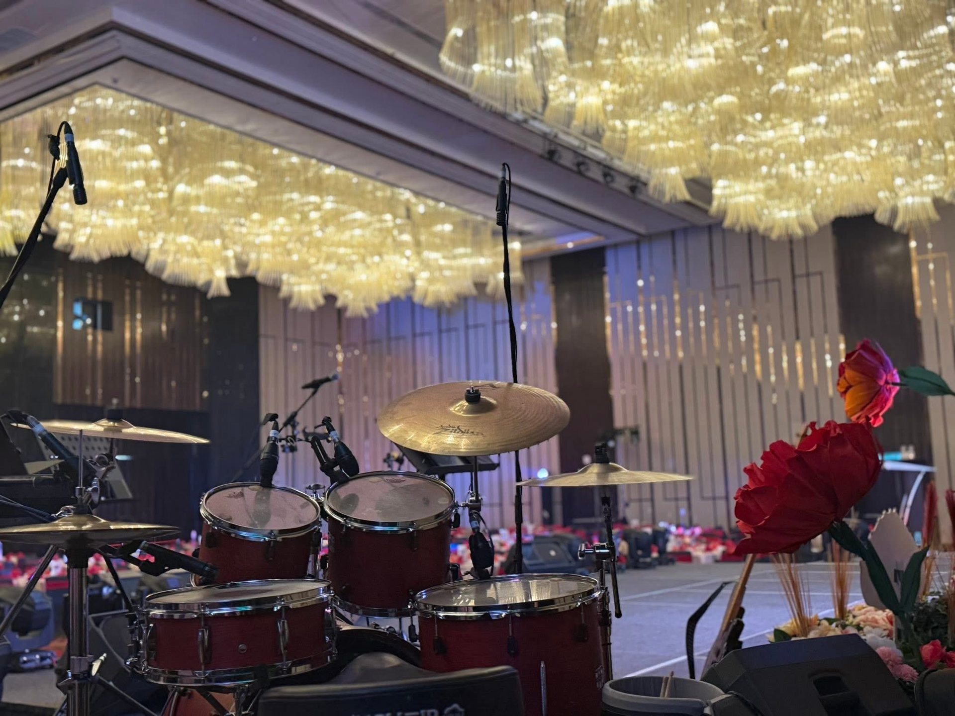 Drum kit set up on a ballroom stage under chandeliers
