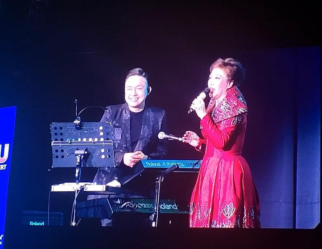 Pianist accompanying a vocalist in a red gown on a concert stage