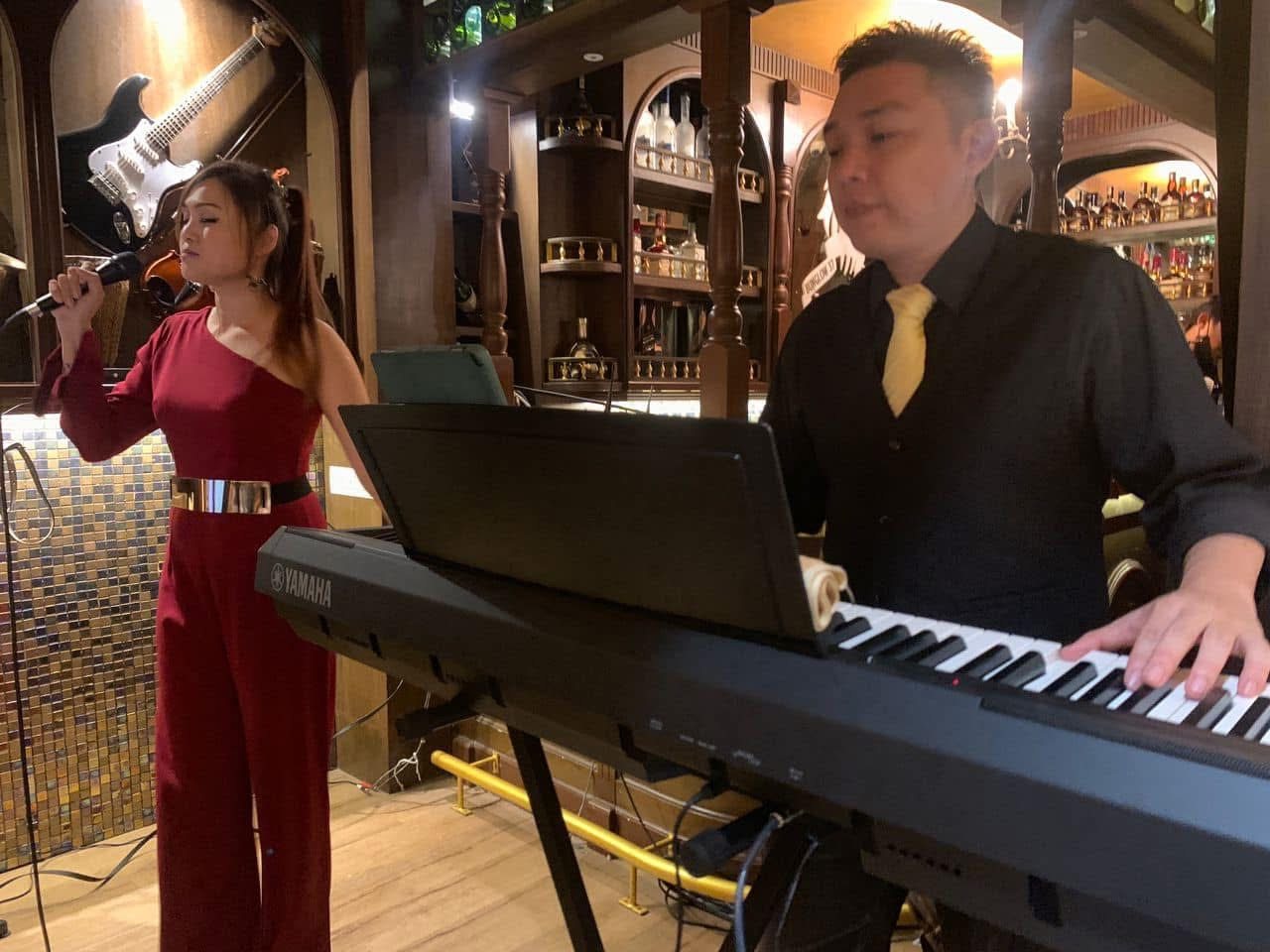 Vocalist in a red dress singing with a keyboard player at a wedding dinner
