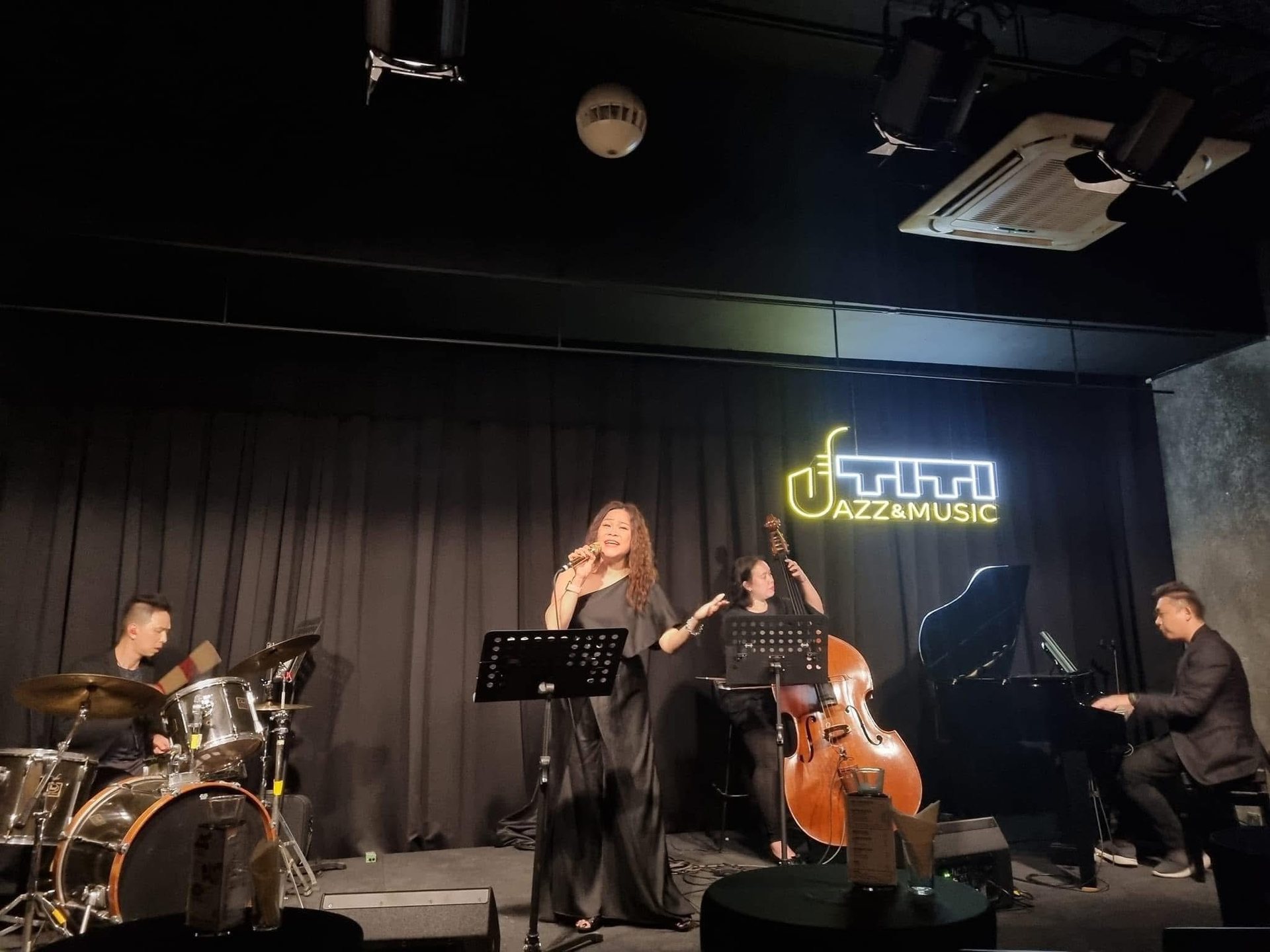 Jazz band with vocalist, double bass, drums and grand piano on stage