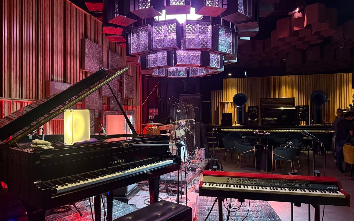 Black grand piano and red stage keyboard set up in a warm, elegant lounge