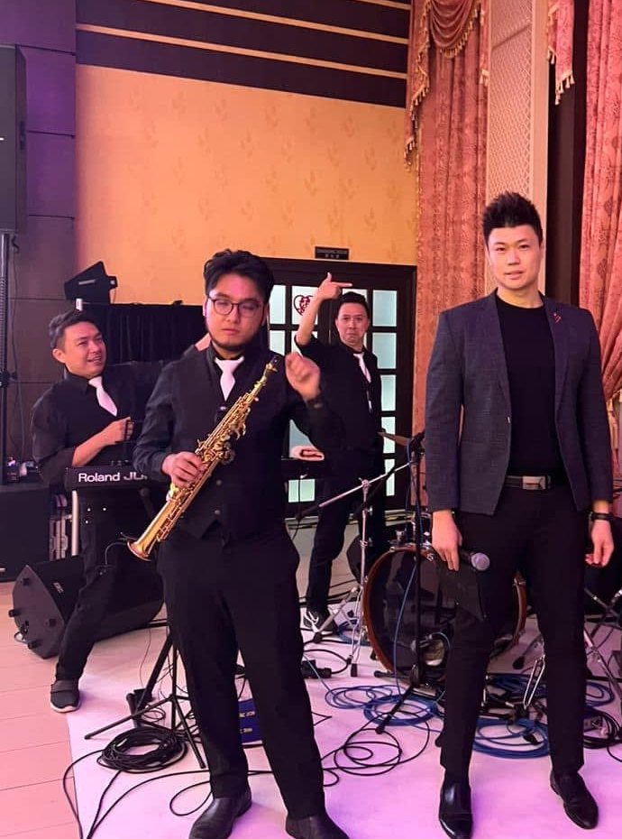 Saxophonist and male vocalist performing with the band at a wedding reception
